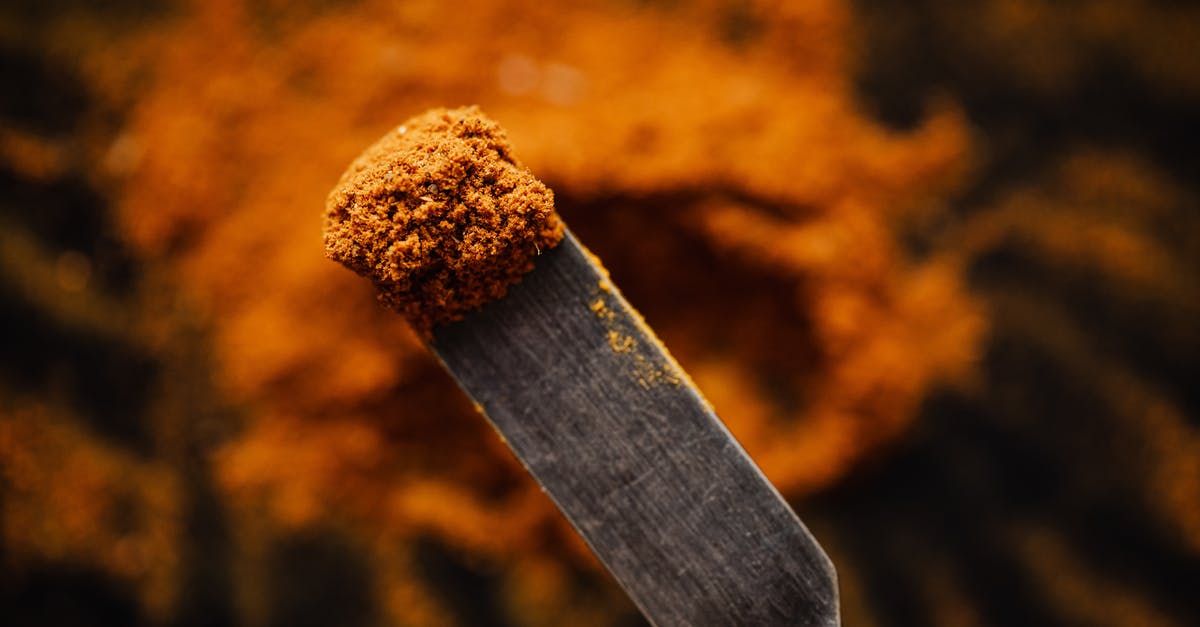 Ground turkey raw in crockpot - Closeup spatula with sample of ground paprika taken from heap in dark barn Ground turkey raw in crockpot - Closeup spatula with sample of ground paprika taken from heap in dark barn