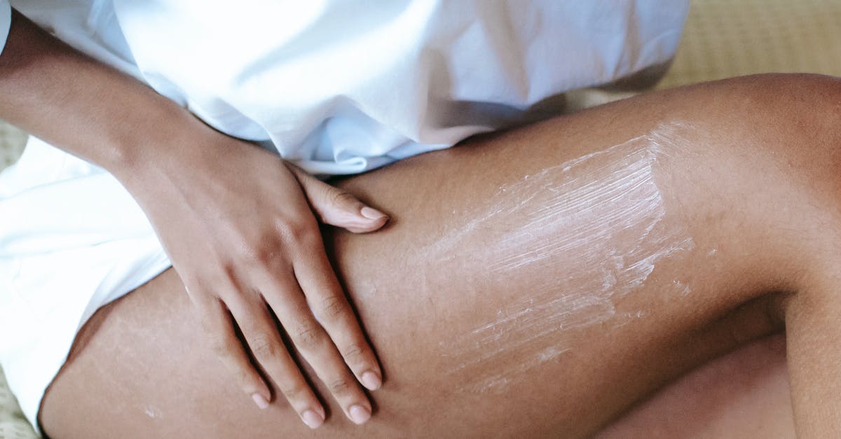 Hazelnut spread preservation - Woman massaging leg with lotion in bedroom Hazelnut spread preservation - Woman massaging leg with lotion in bedroom