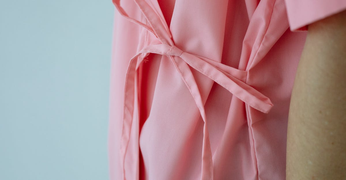 Help freezing chicken breasts - Crop unrecognizable female patient in pink gown with pink ribbon standing against white background Help freezing chicken breasts - Crop unrecognizable female patient in pink gown with pink ribbon standing against white background