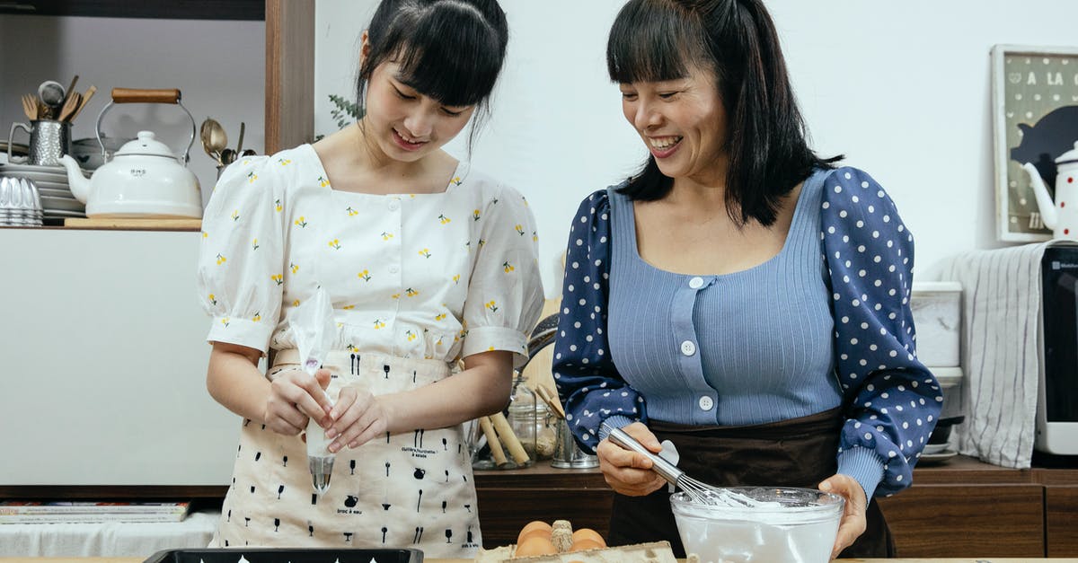 Help in identifying Scandinavian dessert recipe - Happy middle aged Asian female in casual clothes with teenage daughter smiling while preparing tasty meringue cookies in kitchen Help in identifying Scandinavian dessert recipe - Happy middle aged Asian female in casual clothes with teenage daughter smiling while preparing tasty meringue cookies in kitchen