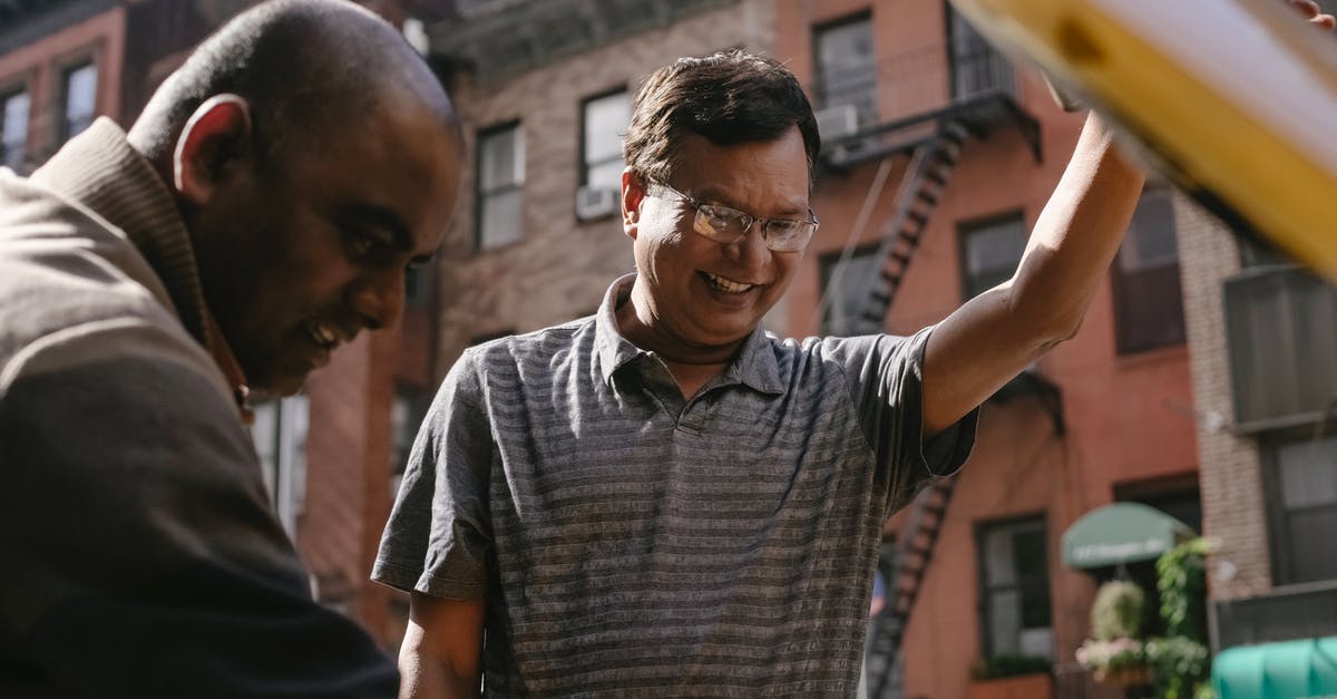 Help me fix my flatbread - Cheerful ethnic man repairing broken car with friend Help me fix my flatbread - Cheerful ethnic man repairing broken car with friend