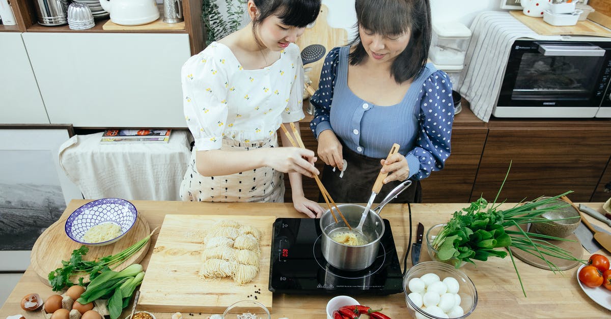 High sodium Udon noodles - High angle glad Asian females in stylish aprons with chopsticks boiling homemade noodles in saucepan on tabletop stove while cooking Asian dish together in contemporary kitchen High sodium Udon noodles - High angle glad Asian females in stylish aprons with chopsticks boiling homemade noodles in saucepan on tabletop stove while cooking Asian dish together in contemporary kitchen