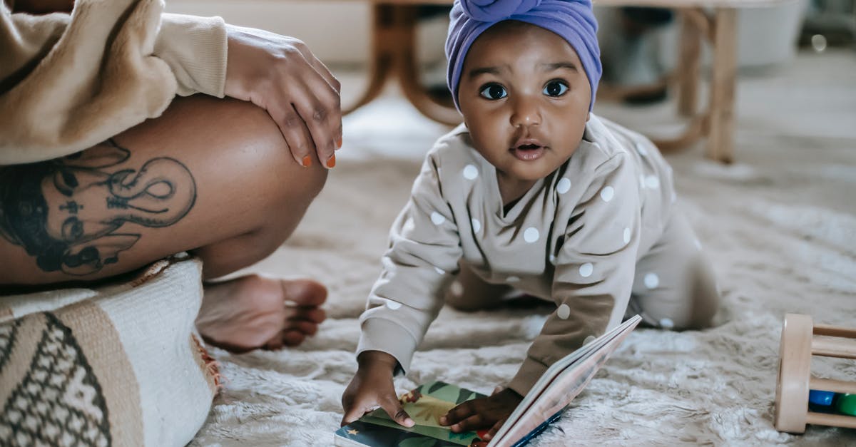 Holes inside a sweet potato - Cute African American toddler on rug with interesting book looking at camera while spending time in room with anonymous black mother Holes inside a sweet potato - Cute African American toddler on rug with interesting book looking at camera while spending time in room with anonymous black mother