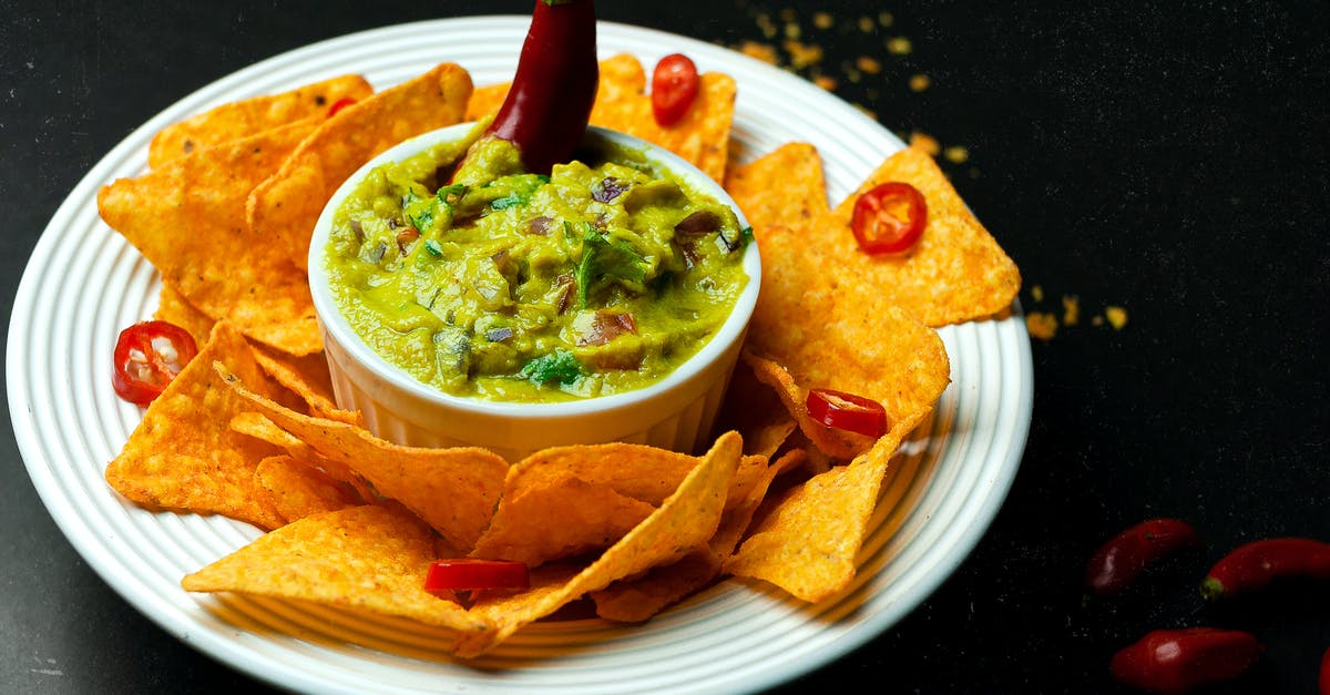 Homemade Pepper Sauce - Suggestion for a serving bottle - High angle of crispy nachos near bowl with guacamole and chili pepper on plate Homemade Pepper Sauce - Suggestion for a serving bottle - High angle of crispy nachos near bowl with guacamole and chili pepper on plate