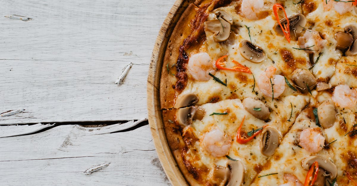 Homemade pizza left out overnight - Appetizing pizza with shrimps and champignon on wooden table Homemade pizza left out overnight - Appetizing pizza with shrimps and champignon on wooden table