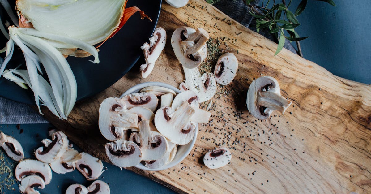 Homemade yeast extract from vegetable stock for nutritional properties - Uncooked mushrooms and onion placed on table with fresh rosemary