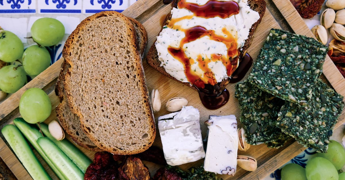 How are strained tomatoes different than tomato sauce? [duplicate] - Top view of wooden cutting board with fresh cucumber slices and black bread loafs with soft tofu cheese near dry seaweed and crunchy pistachios near pineapple guava