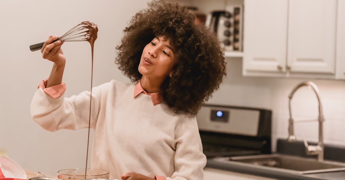 How can I avoid chocolate truffle mix curdling? - Cheerful black woman with batter flowing from whisk How can I avoid chocolate truffle mix curdling? - Cheerful black woman with batter flowing from whisk