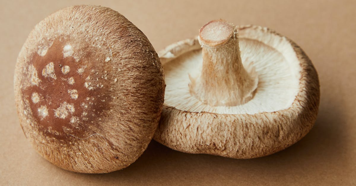 How can I avoid from turning mushrooms brown while freezing it? - High angle of delicious raw mushrooms with spotted caps placed on light brown background How can I avoid from turning mushrooms brown while freezing it? - High angle of delicious raw mushrooms with spotted caps placed on light brown background
