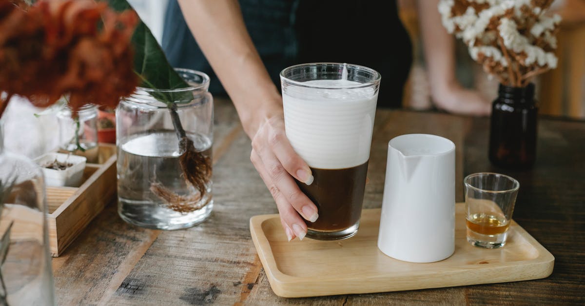 How can I brew a stronger cocoa drink? - Crop anonymous female barista serving fresh brewed iced chocolate coffee with thick layer of fluffy froth on wooden tray with shot of cognac How can I brew a stronger cocoa drink? - Crop anonymous female barista serving fresh brewed iced chocolate coffee with thick layer of fluffy froth on wooden tray with shot of cognac