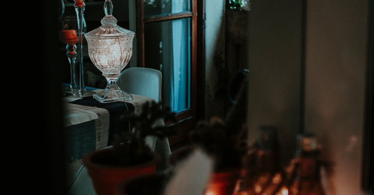 How can I clean dark non-stick pots (e.g. Calphalon)? - Interior of dark room with potted plants on table near elegant glass vase and creative glass candleholders against window