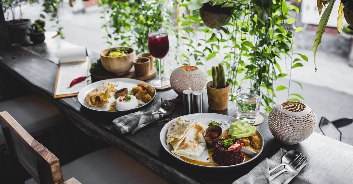 How can I cook parboiled rice in absorption method? - High angle of plates with assorted healthy dishes served on wooden table with cutlery and drinks in stylish tropical cafe