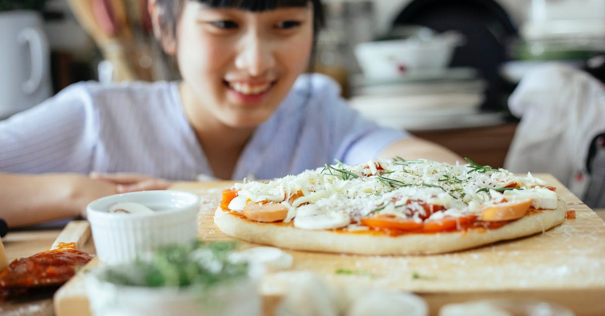 How can I improve my gluten-free pizza dough? - Crop Asian lady smiling and looking at homemade pizza placed on wooden table among various fresh ingredients and utensil in kitchen How can I improve my gluten-free pizza dough? - Crop Asian lady smiling and looking at homemade pizza placed on wooden table among various fresh ingredients and utensil in kitchen