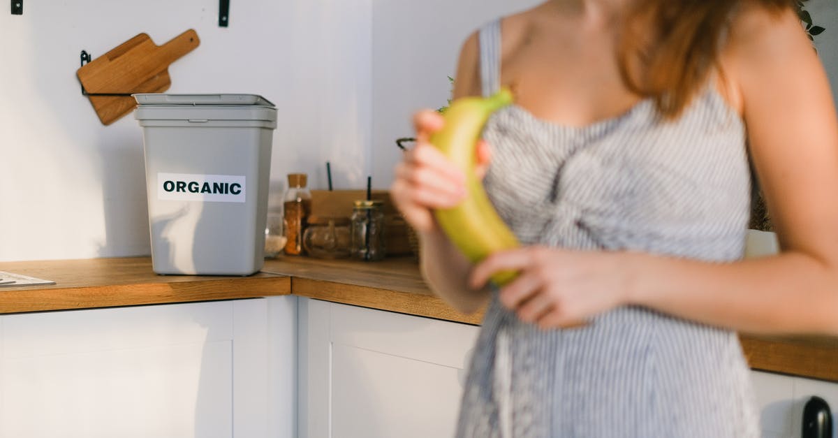 How can I keep flies out of my kitchen? - Crop woman with organic banana in hands standing in kitchen How can I keep flies out of my kitchen? - Crop woman with organic banana in hands standing in kitchen