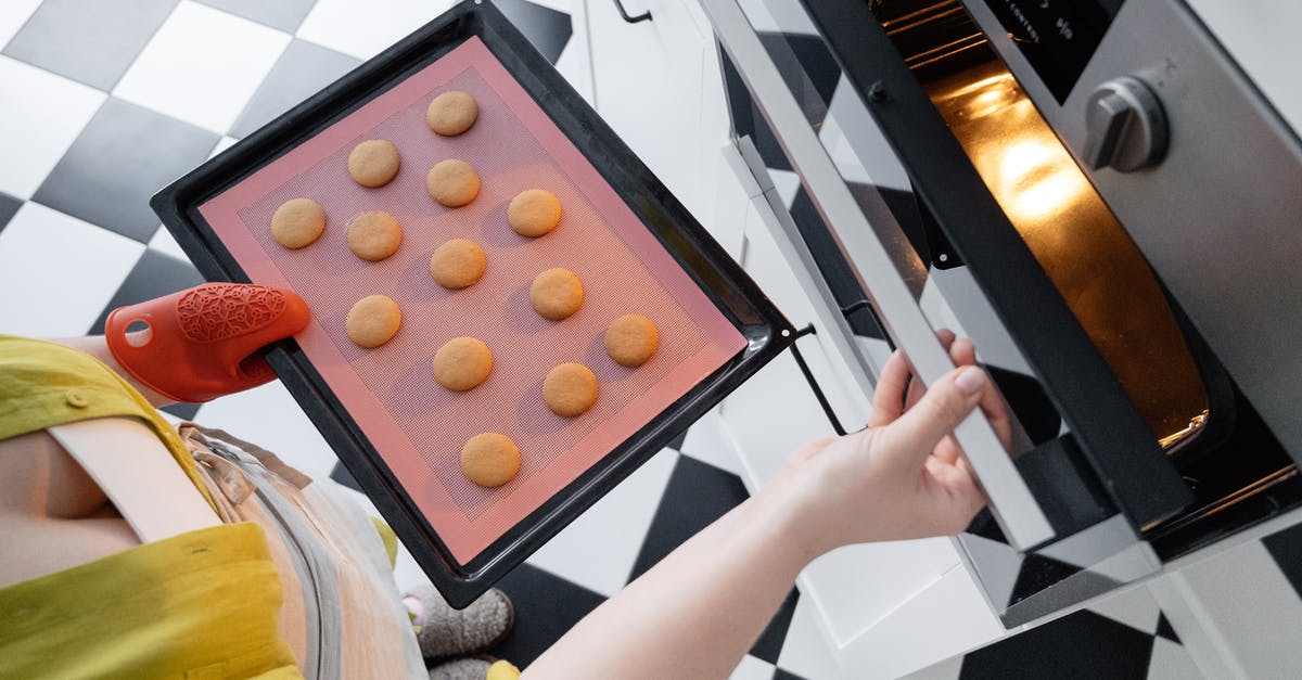 How can I make a really gingery cookie? - From above of crop unrecognizable female opening oven and putting baking pan with uncooked cookies inside oven in kitchen