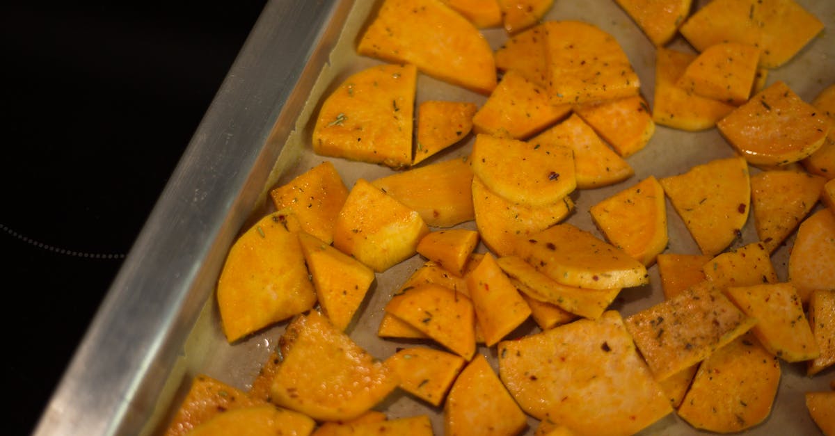 How can I make my homemade potato wedges crispy? - From above of appetizing sliced fried potatoes with spices scattered on oven pan in kitchen