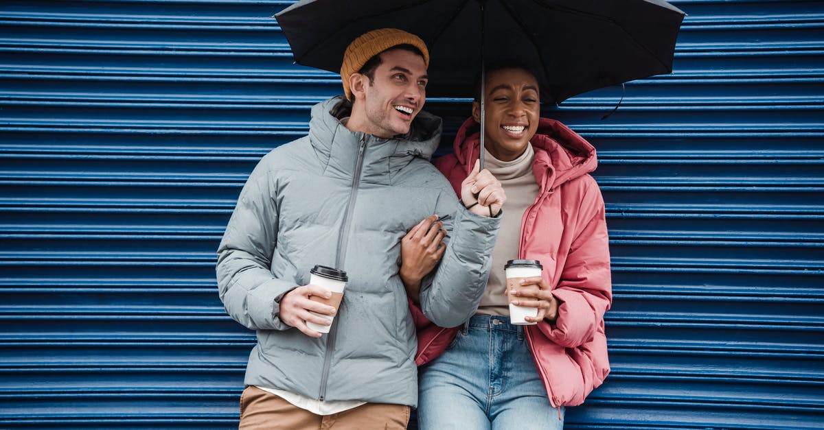 How can I maximize the caffeine content of my coffee? - Happy multiracial couple with umbrella in warm outerwear laughing while standing on street with takeaway beverages in cold rainy weather How can I maximize the caffeine content of my coffee? - Happy multiracial couple with umbrella in warm outerwear laughing while standing on street with takeaway beverages in cold rainy weather