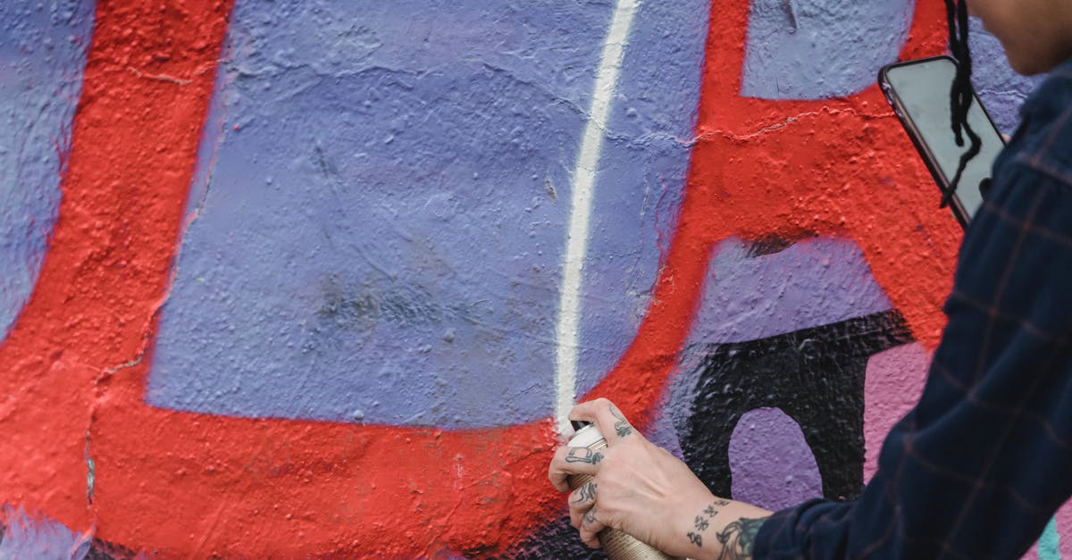 How can I pipe multicolored flowers? - Side view of crop unrecognizable painter spraying paint on colorful wall with patterns while creating graffiti on street of city How can I pipe multicolored flowers? - Side view of crop unrecognizable painter spraying paint on colorful wall with patterns while creating graffiti on street of city