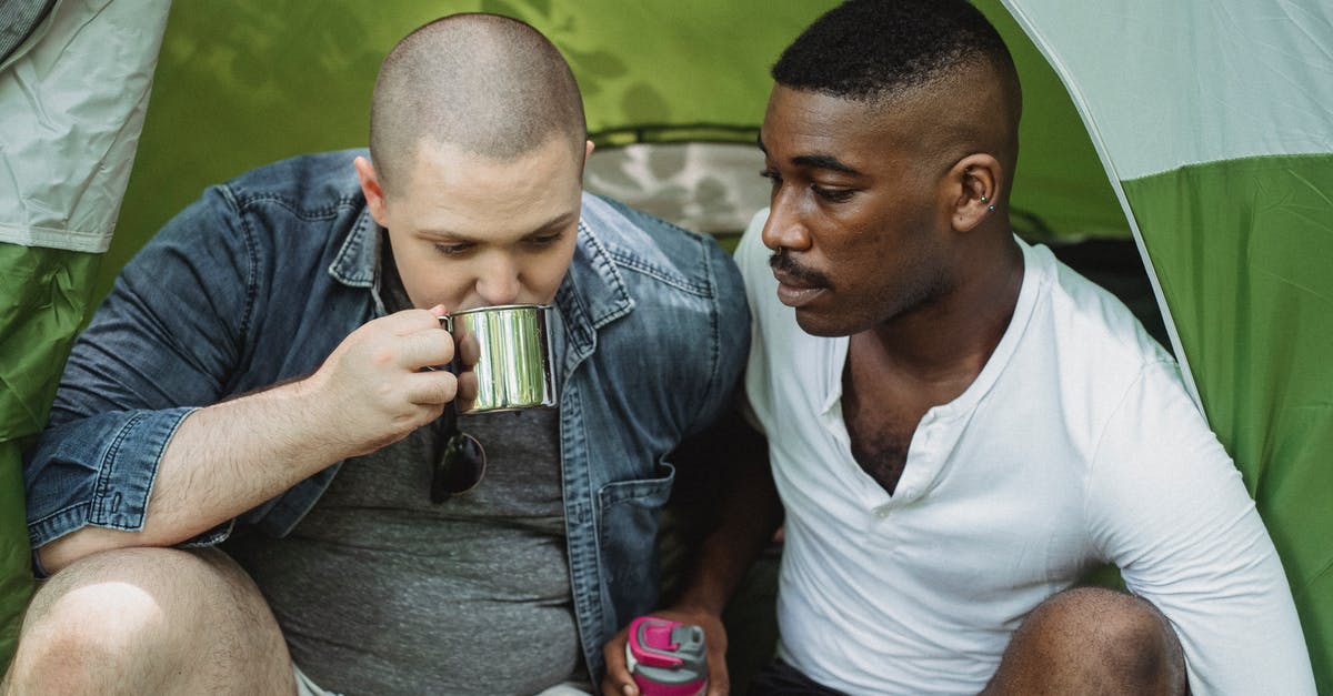 How can I prevent tea stored in a thermos from oversteeping? - Man drinking tea from thermos sitting with black friend