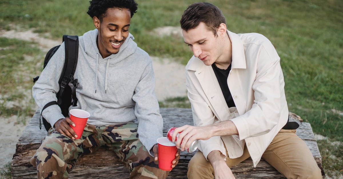 How can I restart my kombucha liquid? - High angle of male pouring carbonated drink from tin can to smiling black friend sitting with red cup How can I restart my kombucha liquid? - High angle of male pouring carbonated drink from tin can to smiling black friend sitting with red cup