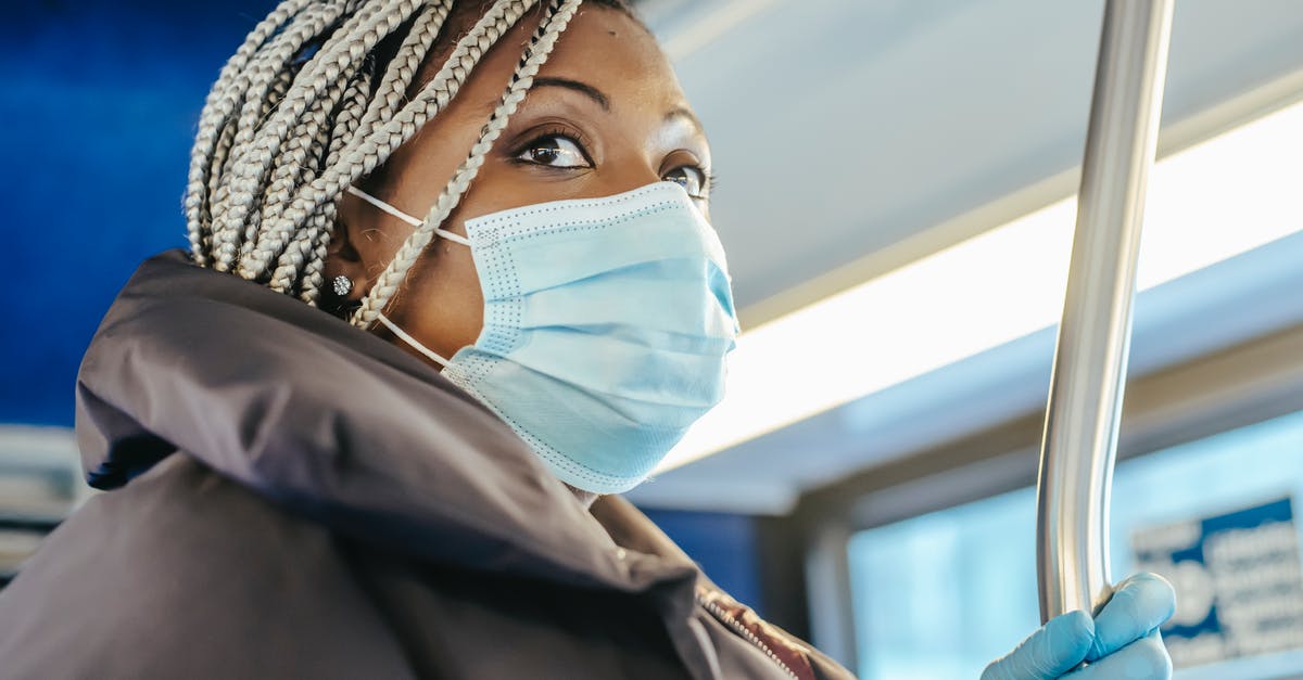 How can I safely transport cooked food in warm weather? [duplicate] - Adult black woman in warm outfit and protective mask with gloves riding on public bus in daytime