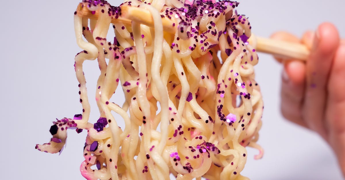 How common is it for people to not have the concept of certain ‘breakfast food’? [closed] - Closeup of crop unrecognizable person holding instant noodles covered with sequins with chopsticks against gray background