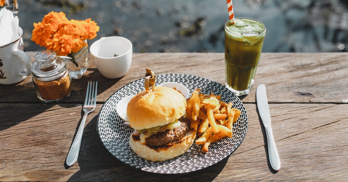 How could I make stuffed french fries? - Plate with appetizing hamburger and french fries placed on lumber table near glass of green drink in outdoor cafe How could I make stuffed french fries? - Plate with appetizing hamburger and french fries placed on lumber table near glass of green drink in outdoor cafe