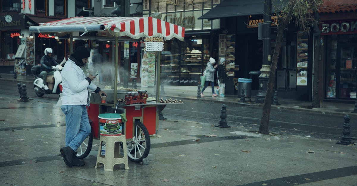 How did people transport food before aluminium foil was invented? - Unrecognizable man selling food in street stall near building