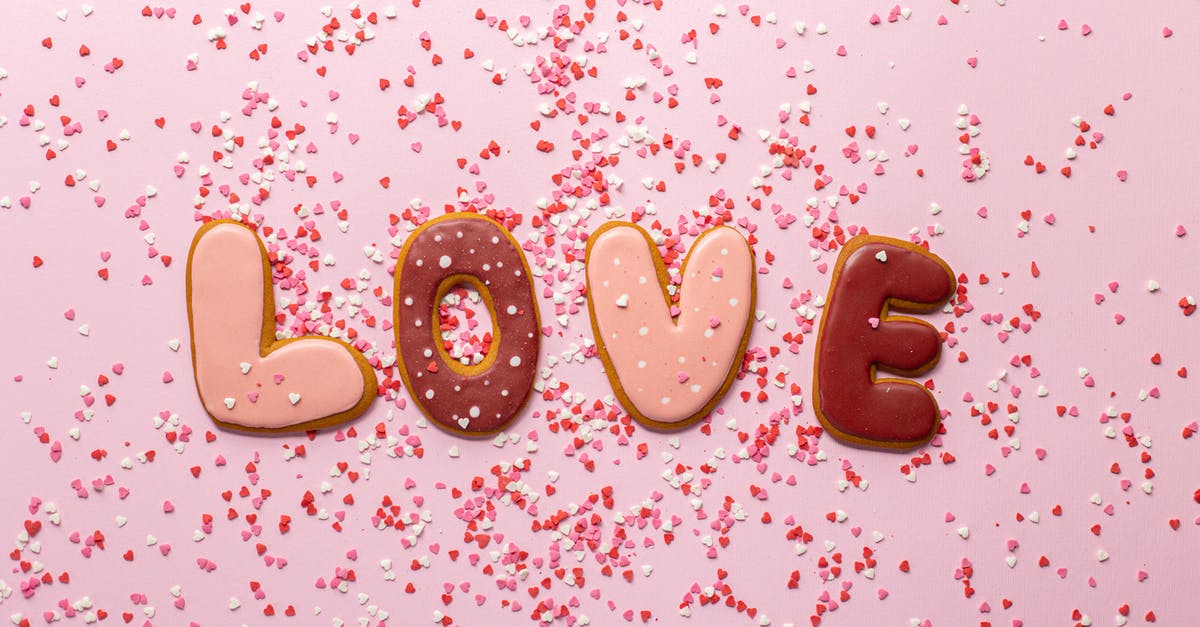 How do I keep Glaze for Gingerbread cookies translucent - Top view of composed cookies making Love inscription with small heart shaped confetti on pink background How do I keep Glaze for Gingerbread cookies translucent - Top view of composed cookies making Love inscription with small heart shaped confetti on pink background
