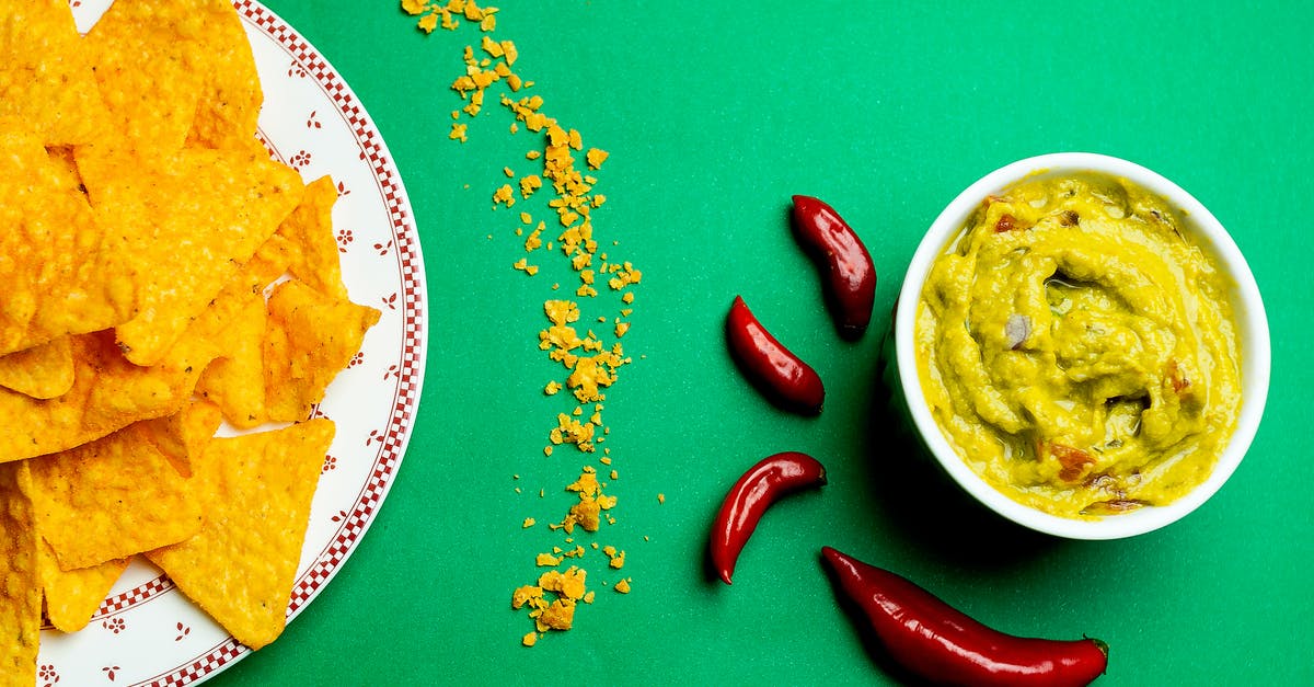 How do I "cool" down very spicy tortilla soup? [duplicate] - Flat lay composition of crispy nachos near guacamole sauce on plate and red chili pepper