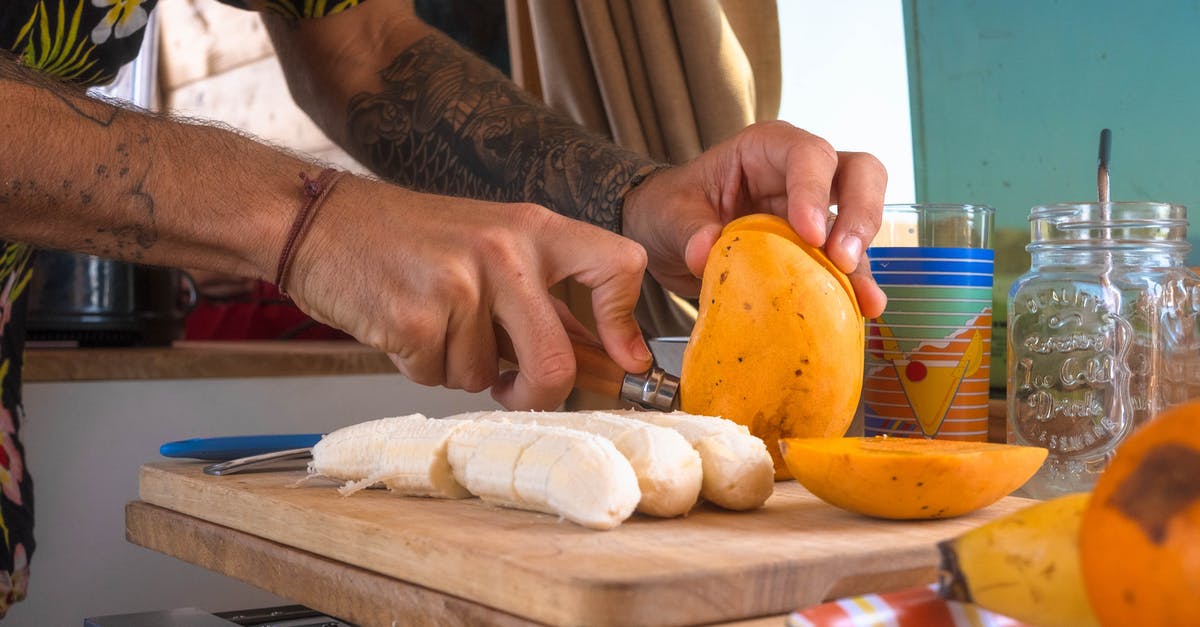 How do I ripen a Mango? - Person Holding Yellow Fruit on Brown Wooden Chopping Board