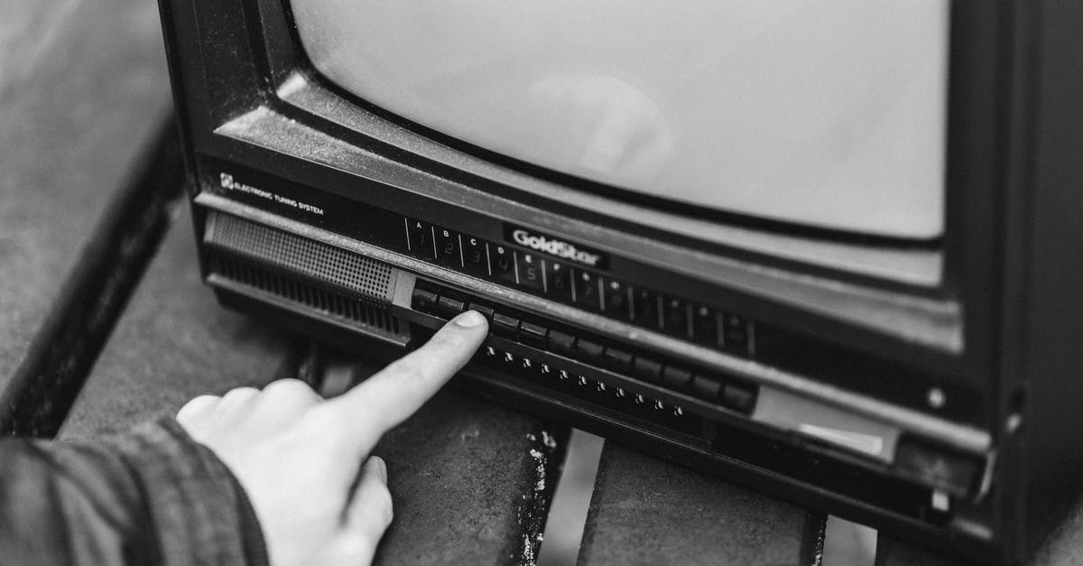 How do I use my lever press correctly? - Black and white from above of anonymous male switching channels on retro black television placed in wooden table on street