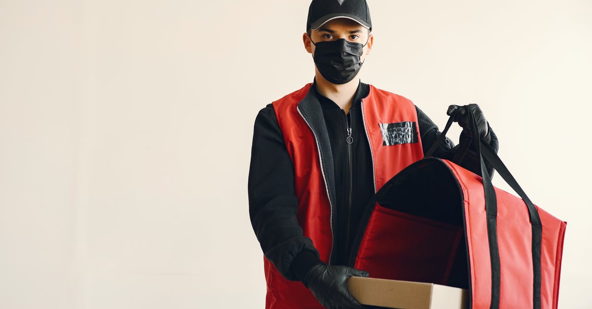 How do you protect a pizza peel? - Young pizza delivery man in uniform and protective mask How do you protect a pizza peel? - Young pizza delivery man in uniform and protective mask