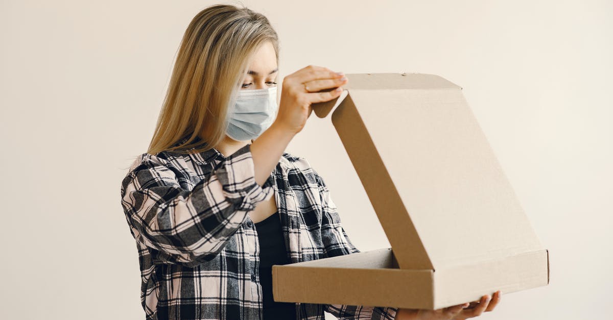 How do you protect a pizza peel? - Young woman in medical mask opening pizza box How do you protect a pizza peel? - Young woman in medical mask opening pizza box
