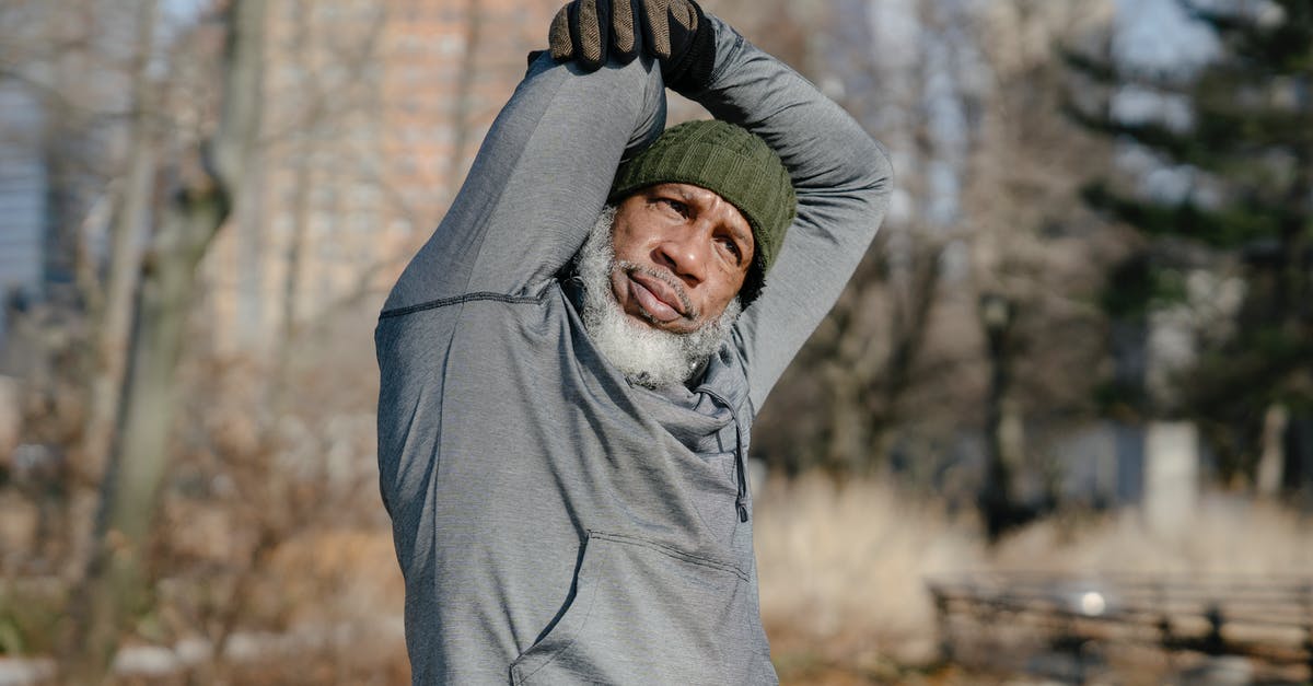 How do you raise your dough in cold seasons? - African American male with white beard in cap looking at camera in park while warming up with raised arms in gloves How do you raise your dough in cold seasons? - African American male with white beard in cap looking at camera in park while warming up with raised arms in gloves