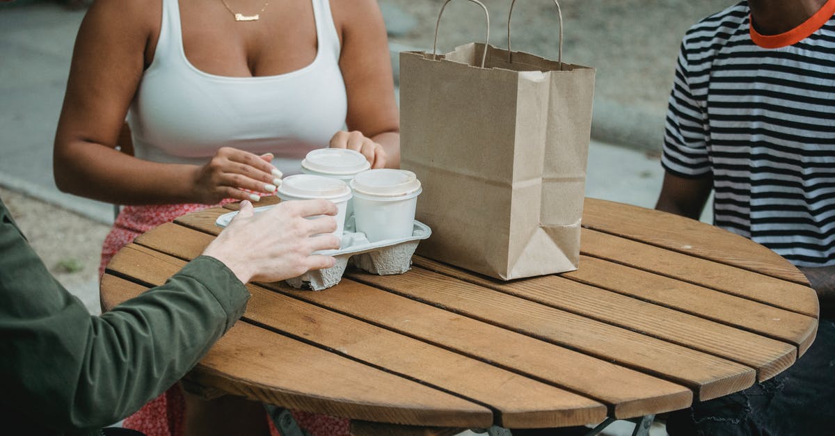 How do you reduce static in a coffee grinder? - Anonymous multiethnic friends having break with takeaway beverages in outdoor cafe