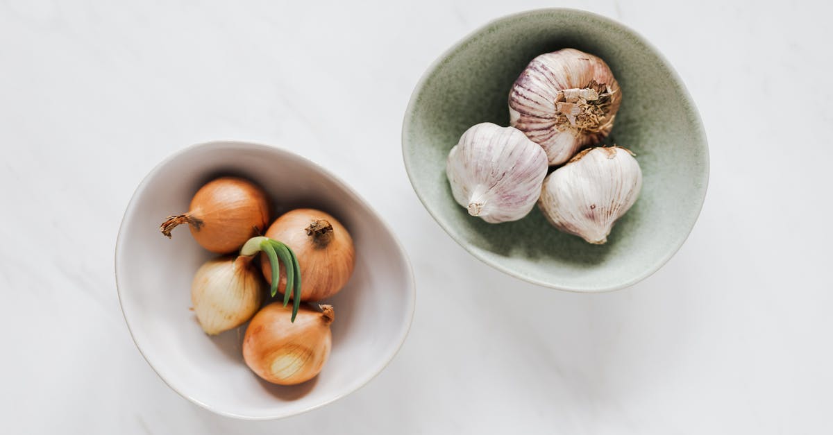 How do you remove garlic smells from your fingers? - Top view of unpeeled raw yellow onion in white bowl and unpeeled raw aromatic garlic in light green bowl placed on marble table How do you remove garlic smells from your fingers? - Top view of unpeeled raw yellow onion in white bowl and unpeeled raw aromatic garlic in light green bowl placed on marble table