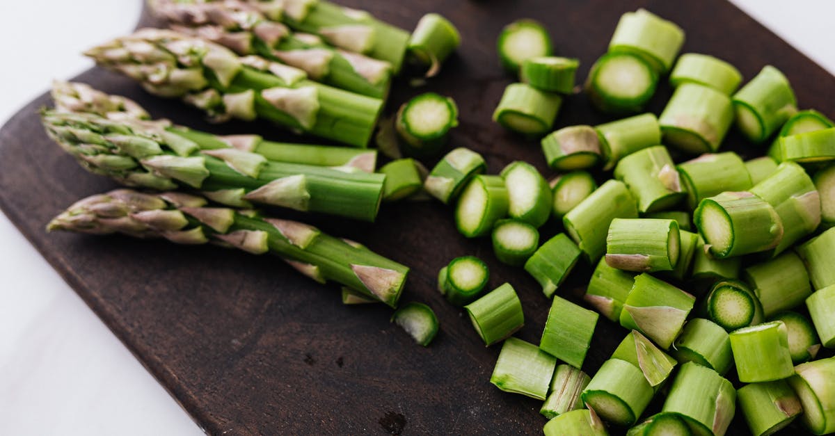 How do you steam vegetables? - Closeup of green chopped stems of asparagus placed on wooden cutting board on white surface How do you steam vegetables? - Closeup of green chopped stems of asparagus placed on wooden cutting board on white surface