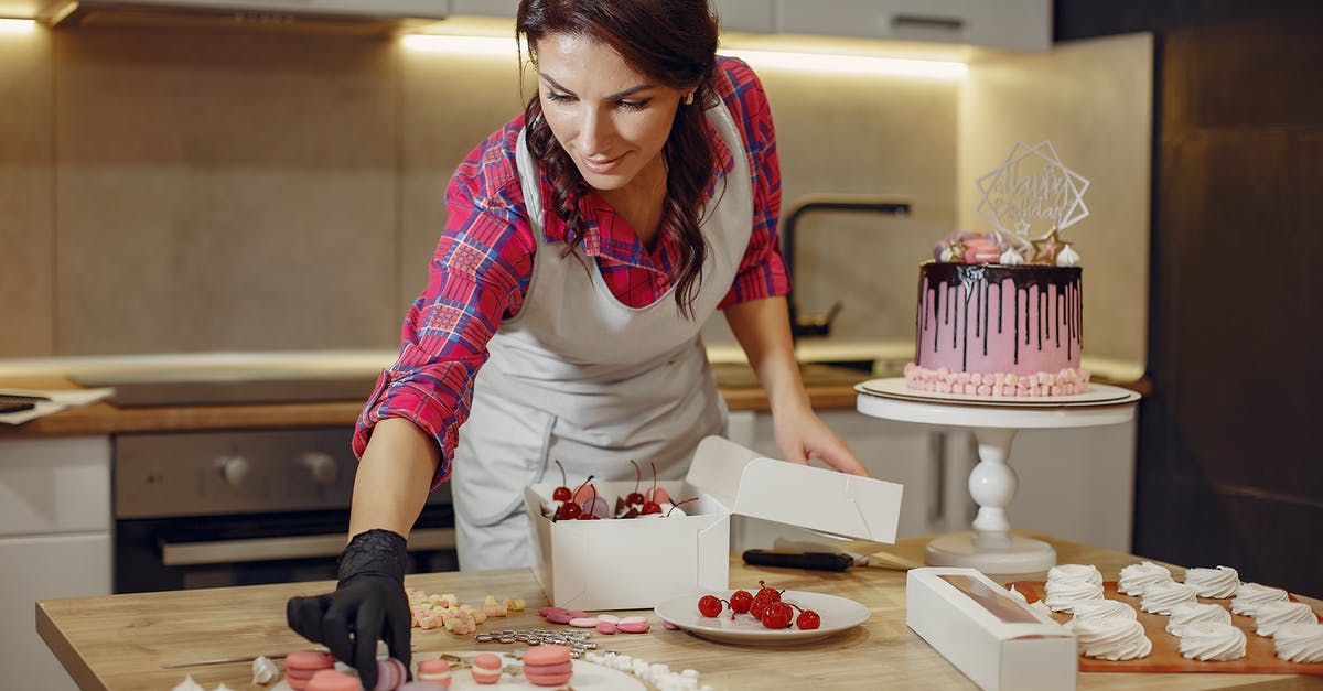 How does a chocolate pudding cake work? - Focused woman decorating cake with macaroons in kitchen How does a chocolate pudding cake work? - Focused woman decorating cake with macaroons in kitchen