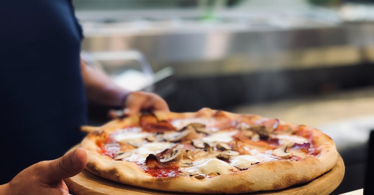 How Does a Hot Water Whipped Pie Crust Work? - Person Holding Whole Pan of Baked Pizza How Does a Hot Water Whipped Pie Crust Work? - Person Holding Whole Pan of Baked Pizza