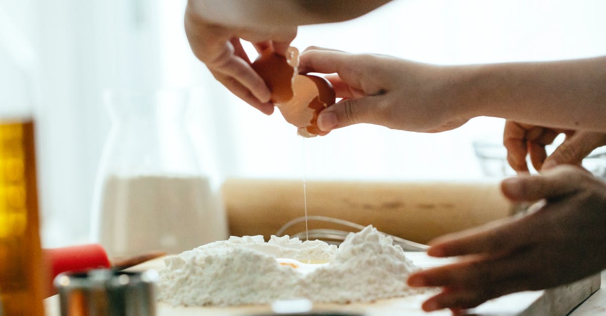 How does a splash of vinegar help when poaching eggs? - Crop young lady breaking eggs in flour for dough How does a splash of vinegar help when poaching eggs? - Crop young lady breaking eggs in flour for dough
