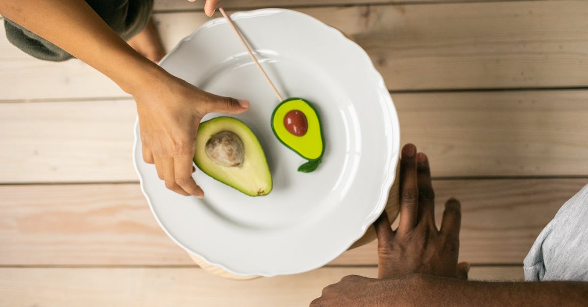 How does imitation cinnamon flavor differ from real? - Top view of crop anonymous African American people near white plate with half of ripe avocado and sweet lollipop with similar shape How does imitation cinnamon flavor differ from real? - Top view of crop anonymous African American people near white plate with half of ripe avocado and sweet lollipop with similar shape