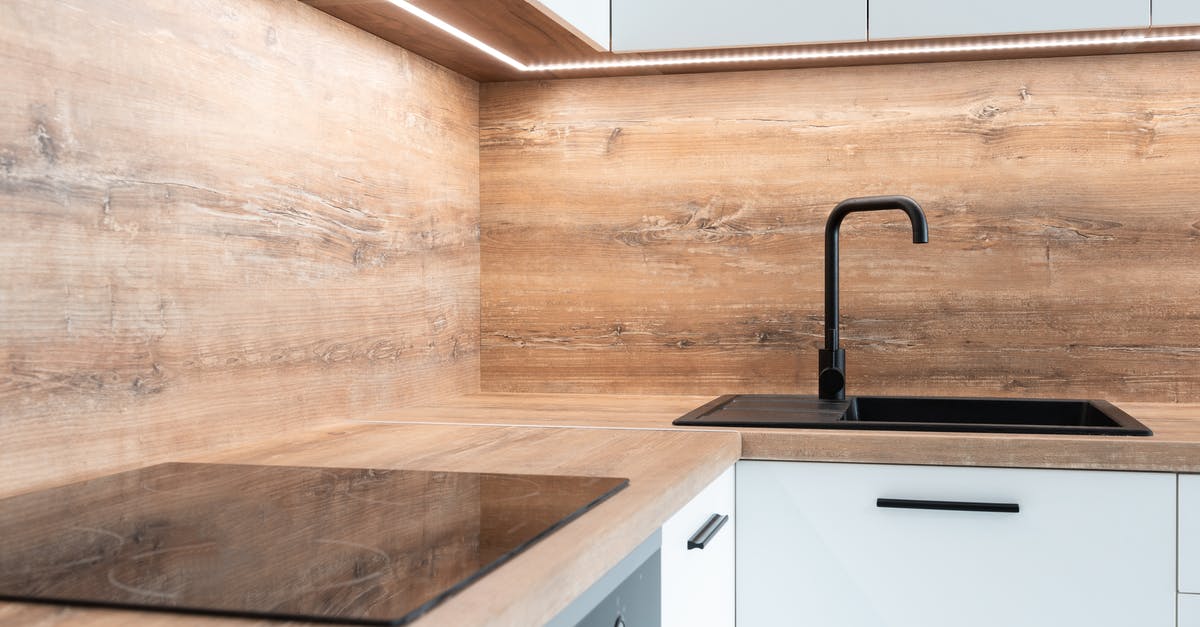 How hot are electric home stoves? - Modern black appliance and sink with faucet in stylish kitchen with wooden walls and white furniture How hot are electric home stoves? - Modern black appliance and sink with faucet in stylish kitchen with wooden walls and white furniture