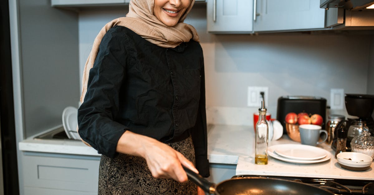 How hot should the oil be when preparing schnitzel? - Crop glad ethnic woman cooking in modern kitchen How hot should the oil be when preparing schnitzel? - Crop glad ethnic woman cooking in modern kitchen