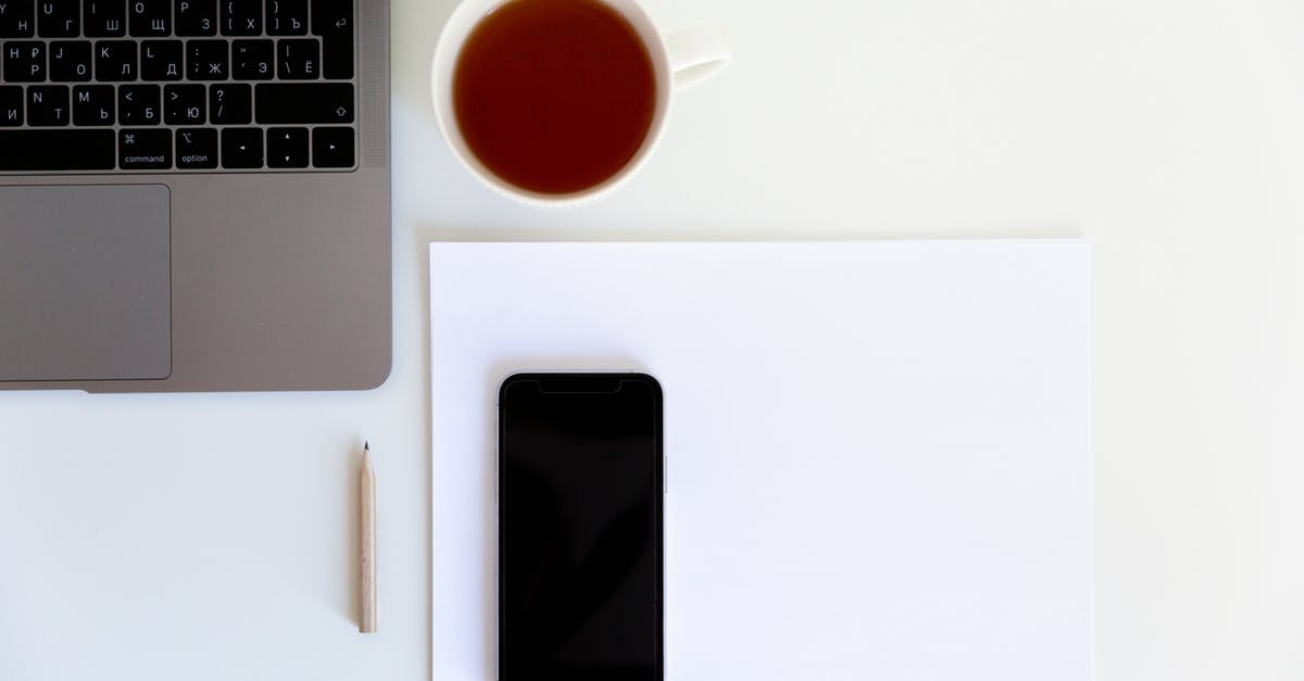 How is British tea prepared? - Workplace with smartphone placed on white paper with cup of tea aside near laptop and pencil How is British tea prepared? - Workplace with smartphone placed on white paper with cup of tea aside near laptop and pencil