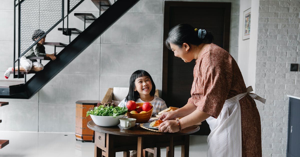 How is starch content of some vegetables reduced by cooking? - Cheerful little Asian girl sitting at table while grandmother serving lunch with fresh veggies How is starch content of some vegetables reduced by cooking? - Cheerful little Asian girl sitting at table while grandmother serving lunch with fresh veggies