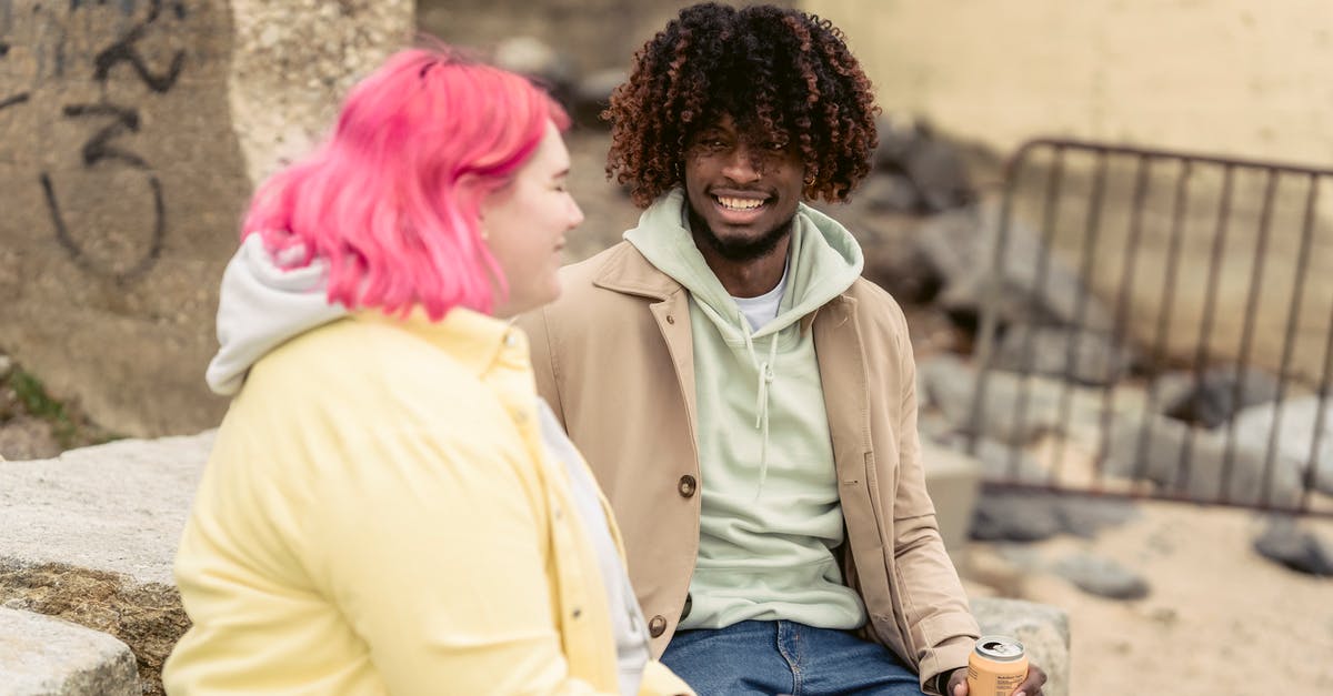 How long before intended date of use can a ham be purchased? - Cheerful multiracial couple with cans of soda sitting on stones on embankment near river while spending time together during date