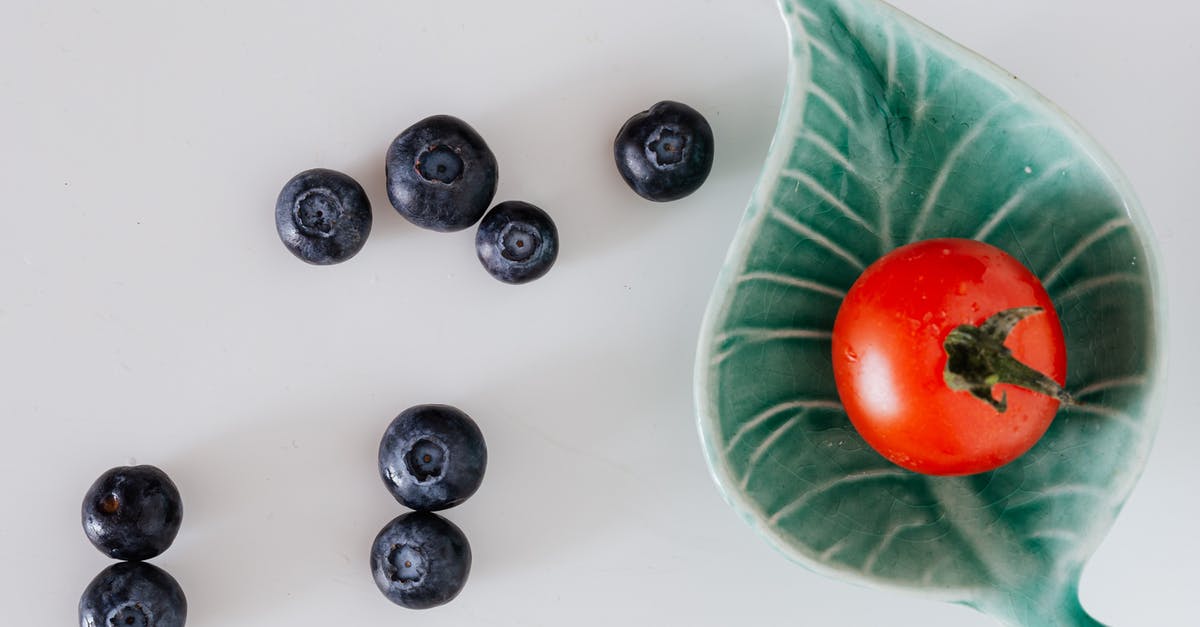 How Long Does Tomato Juice Last? - Minimalistic composition of fresh tomato on small designer platter near blueberries on gray background How Long Does Tomato Juice Last? - Minimalistic composition of fresh tomato on small designer platter near blueberries on gray background