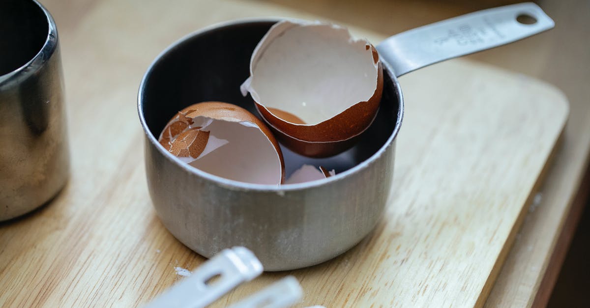 How long should I cook a half goose? - From above of stainless steel scoop with crashed eggshells placed on wooden table in kitchen in daylight