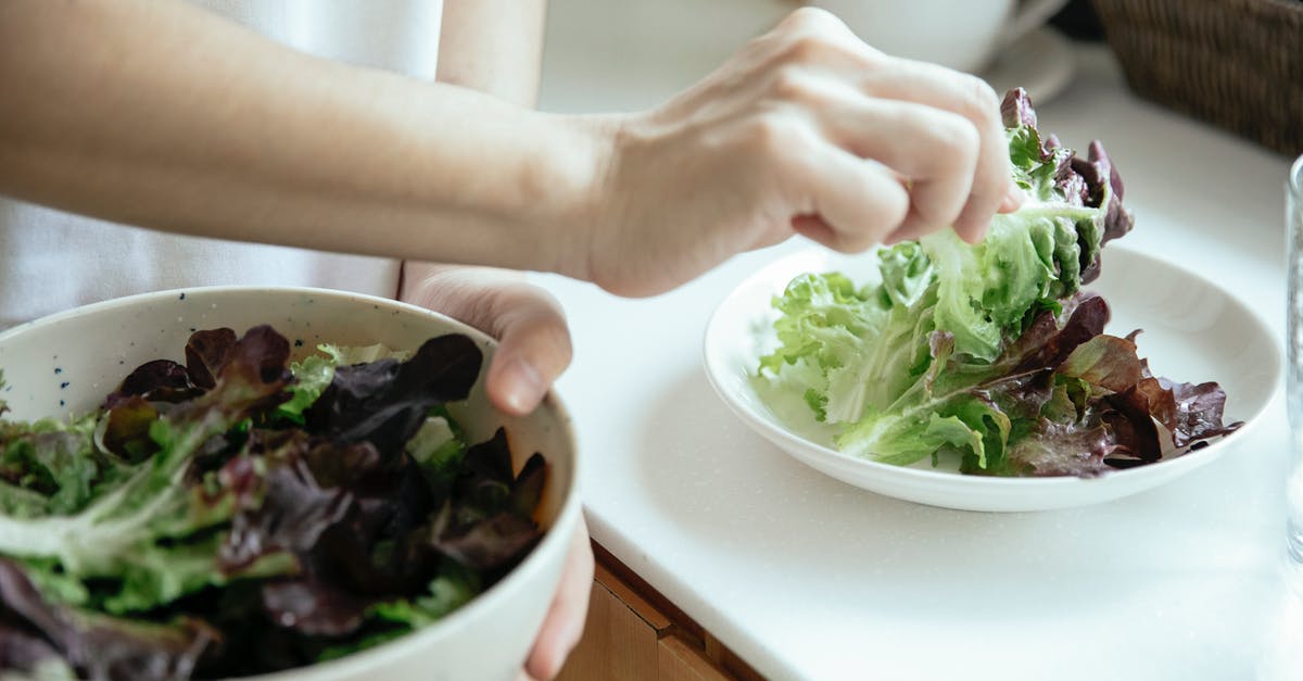 How much salt should I put in a vegetable stew? - From above of crop person putting fresh mix of green salad leaves from bowl into white plate